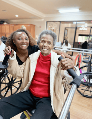 A staff member and resident smiling together in an activity room