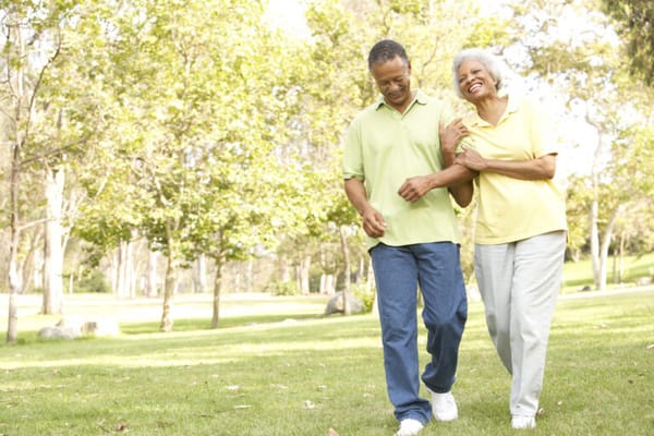 Two seniors walking together in a sunny park