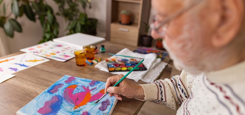 Senior resident painting in an activity room