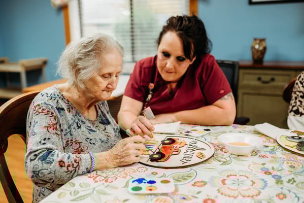A resident painting with a staff member in an activity room