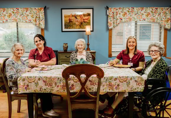 Residents and staff gathered around a colorful dining table