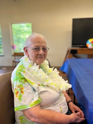 Senior resident wearing a flower lei in an activity room