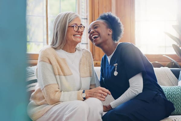 Resident and staff laughing together in a cozy setting