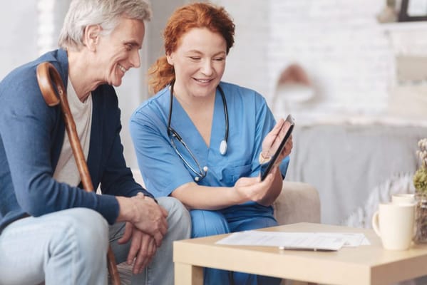 A nurse assisting a senior man in a cozy living area