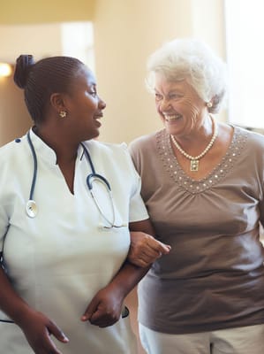 Caregiver and resident smiling together in a hallway