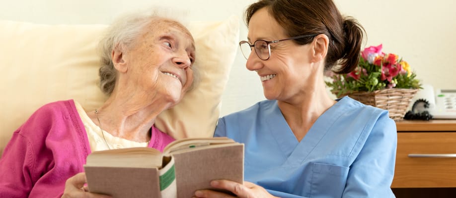 Caregiver reading with a smiling elderly resident