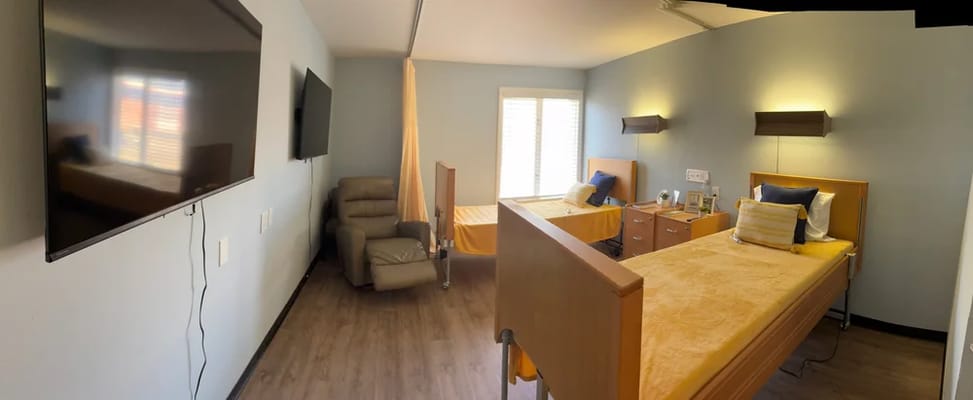 Brightly lit resident bedroom with two beds and a TV