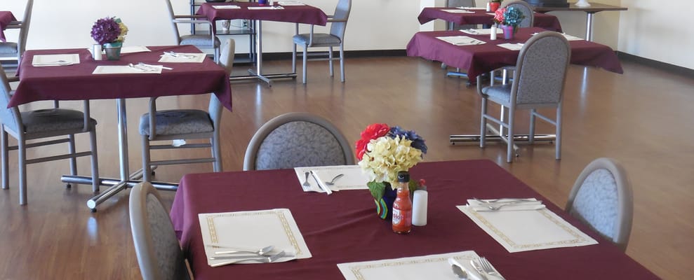 A dining room set up for meals with tables and chairs