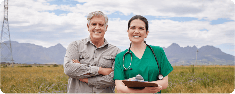 A nurse and resident smiling outdoors in a field