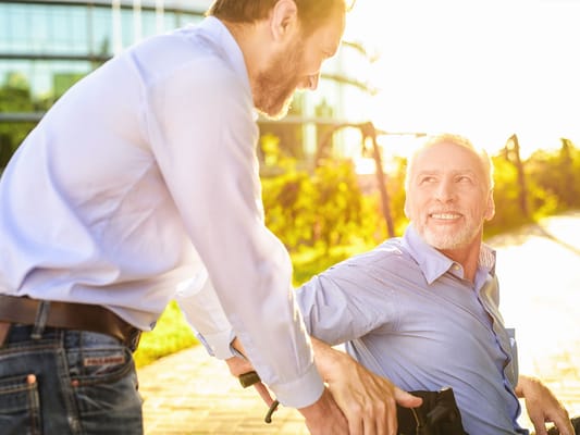 A caregiver assisting a smiling senior outdoors