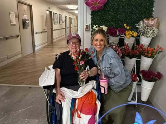 Resident and staff member posing with flowers