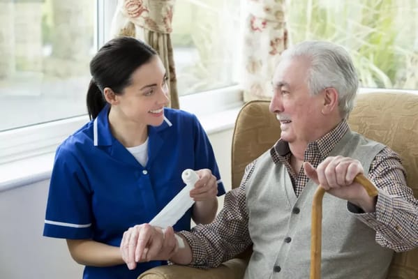 Nurse assisting a resident with care in a sunny room