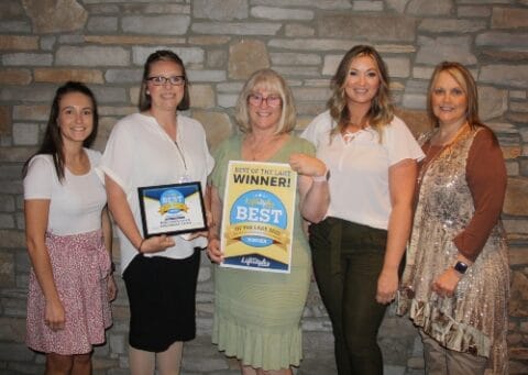 Staff celebrating award with a certificate