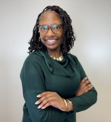 A staff member smiling in a green sweater