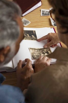 Two residents examining old photos in a scrapbook