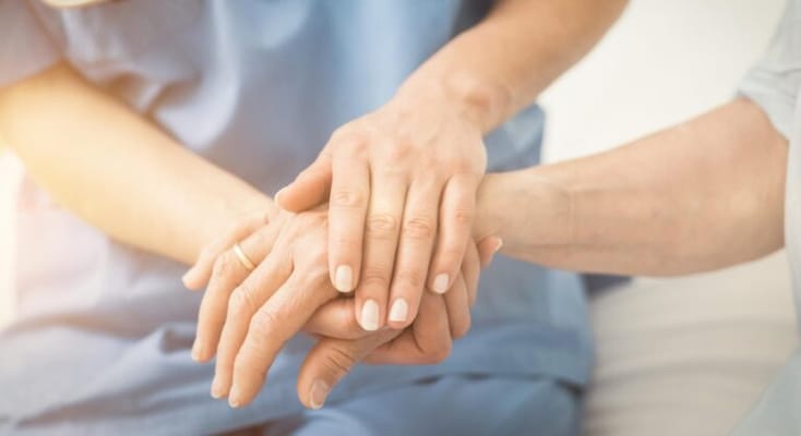Hands of a caregiver and resident holding together