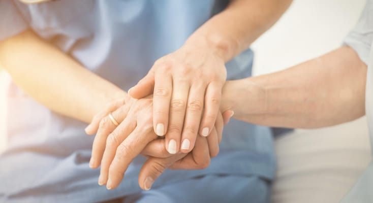 Hands of a caregiver and resident holding together