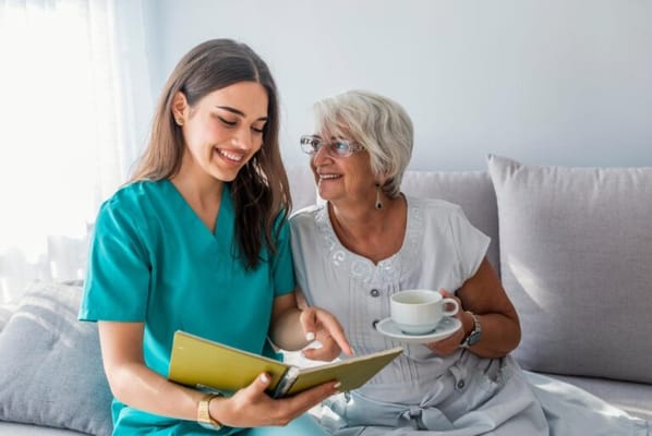 A staff member reading to a resident with a cup of tea