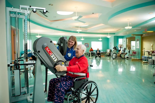 Resident participating in exercise with staff assistance