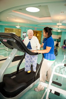 A resident using a treadmill with staff assistance