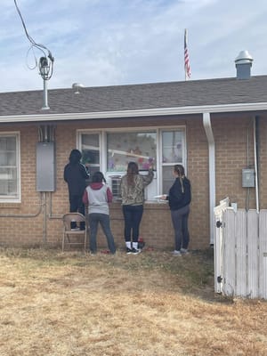 Volunteers decorating windows at a senior living facility