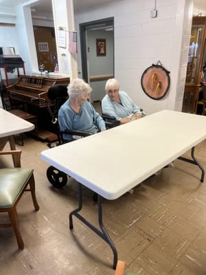 Two female residents sitting at a table in the activity room