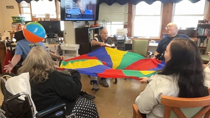 Residents enjoying a colorful group activity with a parachute