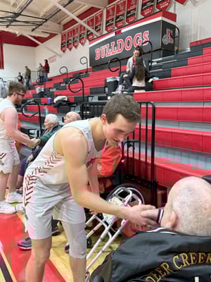 A basketball player interacting with a senior in a gym
