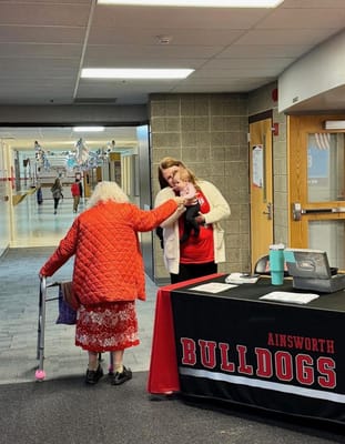 Resident interacting with staff and a child in a hallway