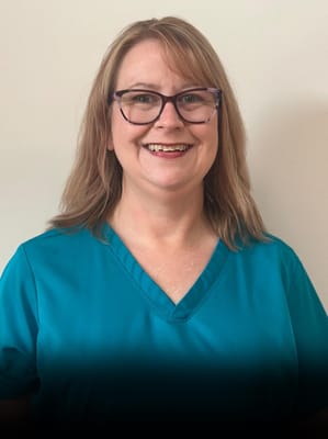 Staff member smiling in a teal uniform