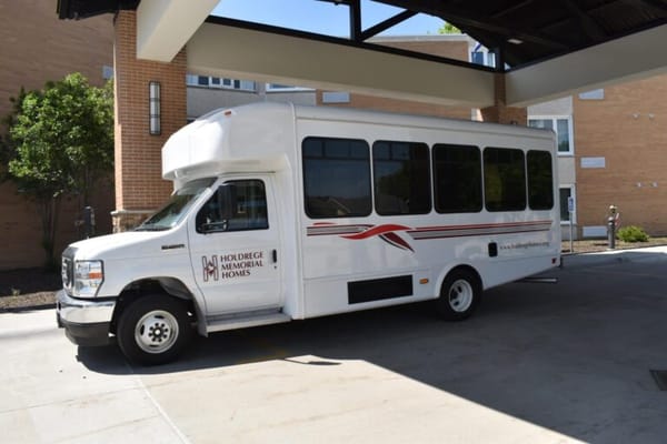 Facility shuttle bus parked under a covered entrance
