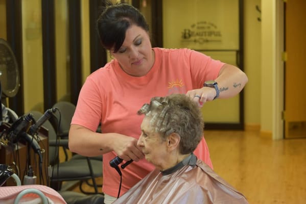 Staff member styling a resident's hair in the salon