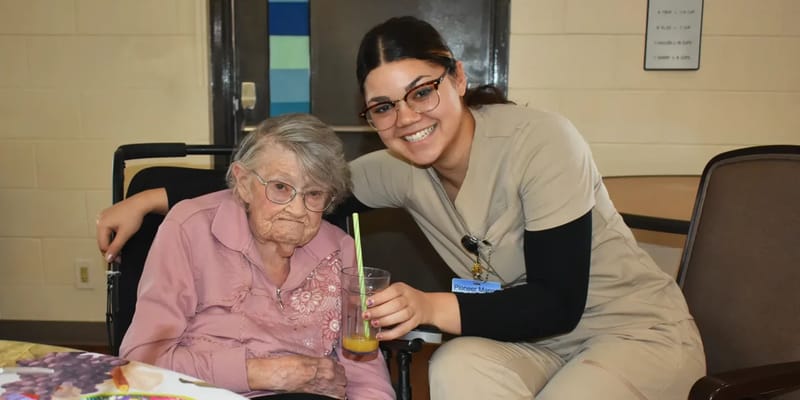 A caregiver posing with a resident in a cozy environment