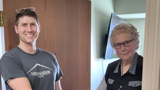 Staff member and resident smiling in a hallway