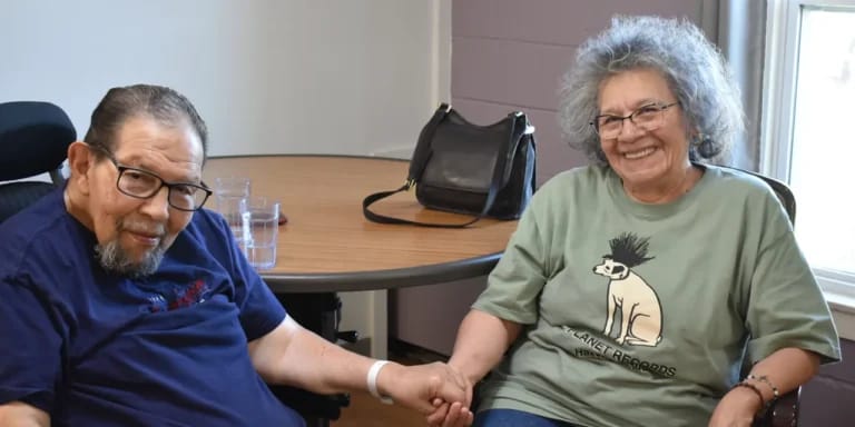 Two residents smiling while holding hands in a common area