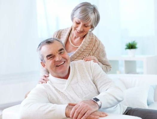 Two smiling seniors in a bright living area