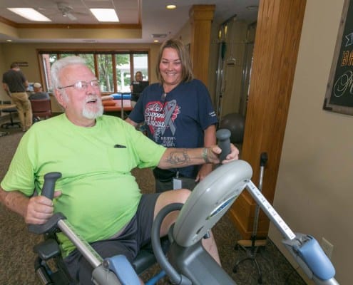Resident exercising with staff assistance in a gym
