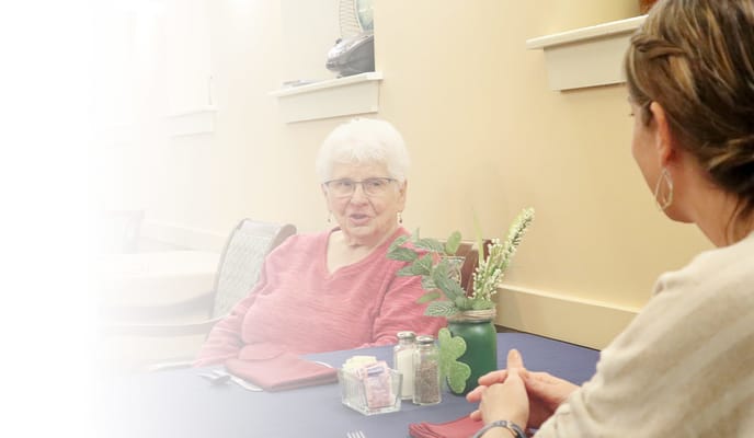 Resident chatting with staff in a cozy dining area