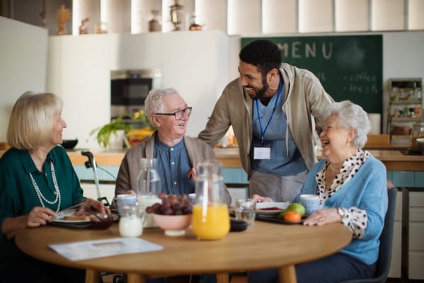 Residents enjoying a meal with staff in a cozy dining area