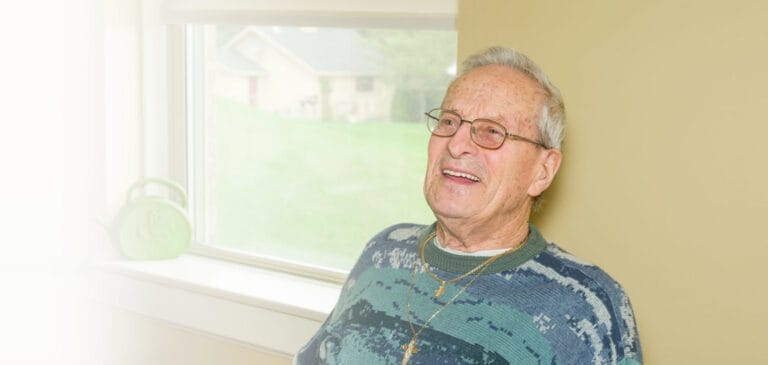 Smiling resident sitting by a window in a cozy room