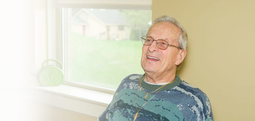 Smiling resident sitting by a window in a cozy room