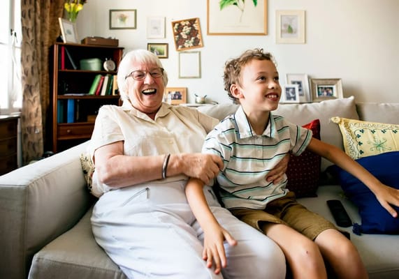 Joyful elderly woman with a young boy on a couch