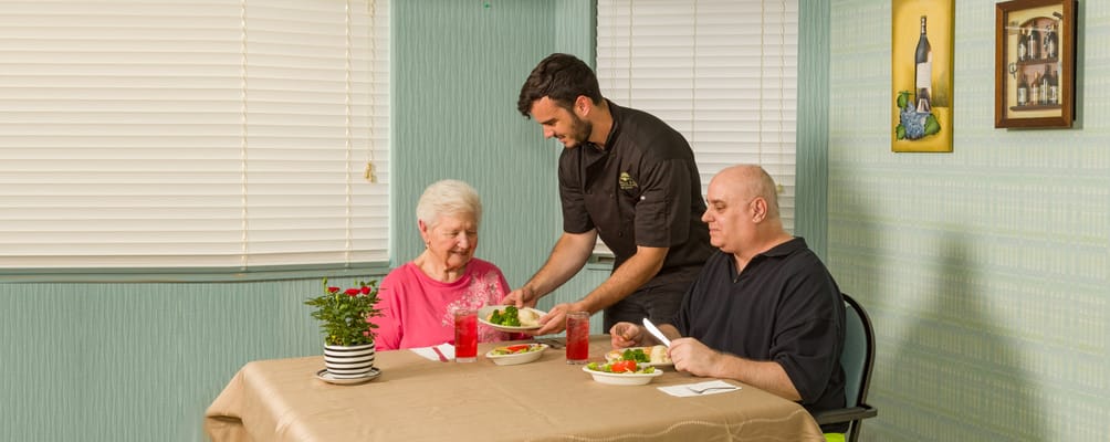 Residents enjoying a meal with staff in a dining area