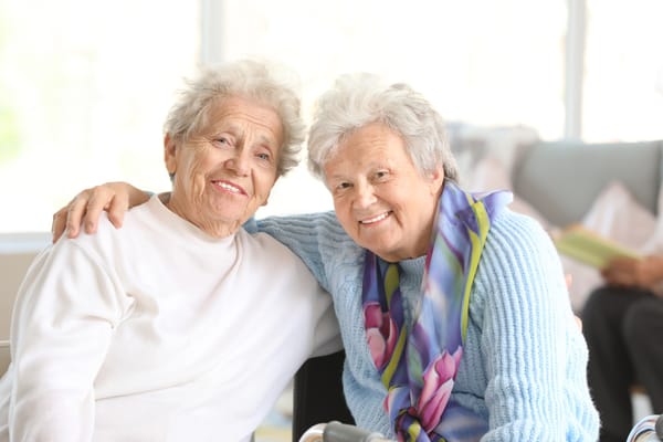 Two senior women smiling together in a cozy setting
