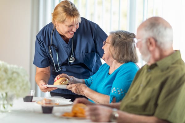 Caregiver interacting with two happy residents during meal