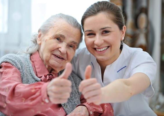 Resident and caregiver giving thumbs up in a bright setting