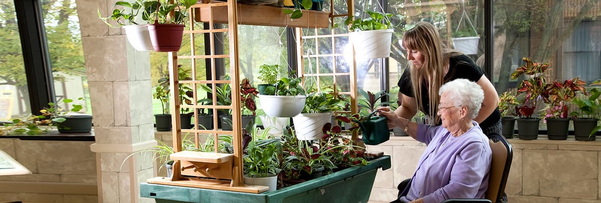 A resident and staff member gardening indoors together