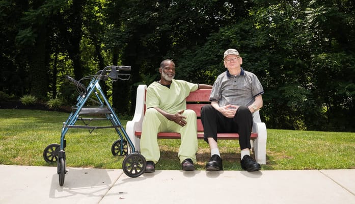 Two residents sitting on a bench in a garden