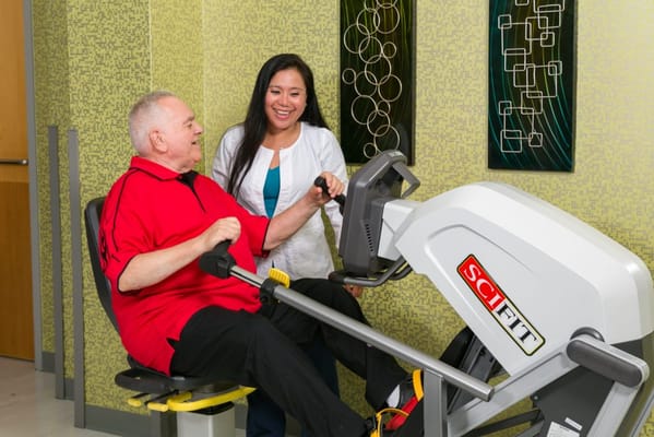 Resident exercising with staff assistance in activity room