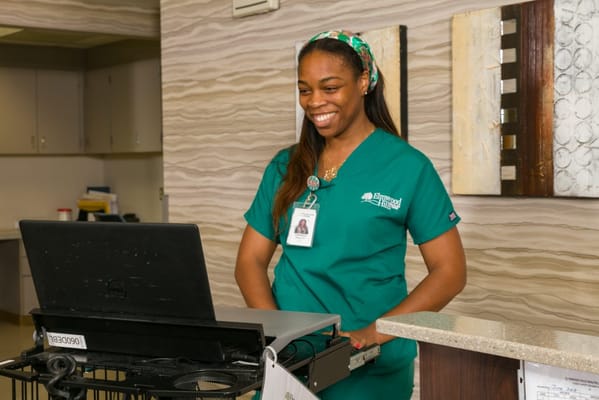 A nurse smiling at the reception desk